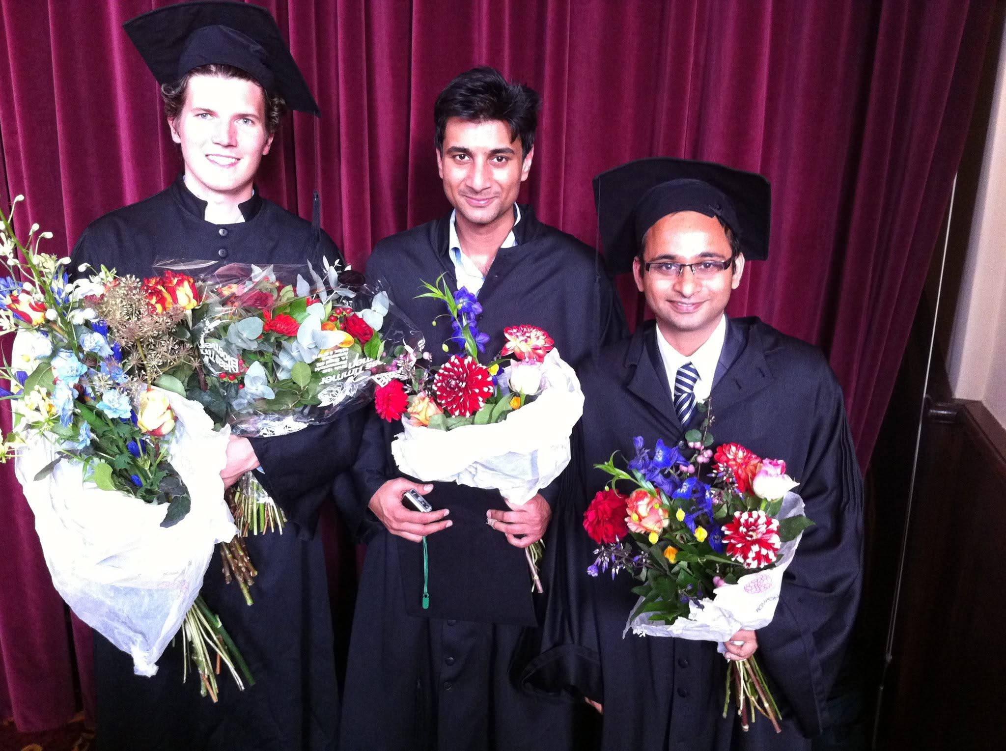 Harish Kumar at MSc graduation ceremony with two classmates, all holding bouquets in academic gowns